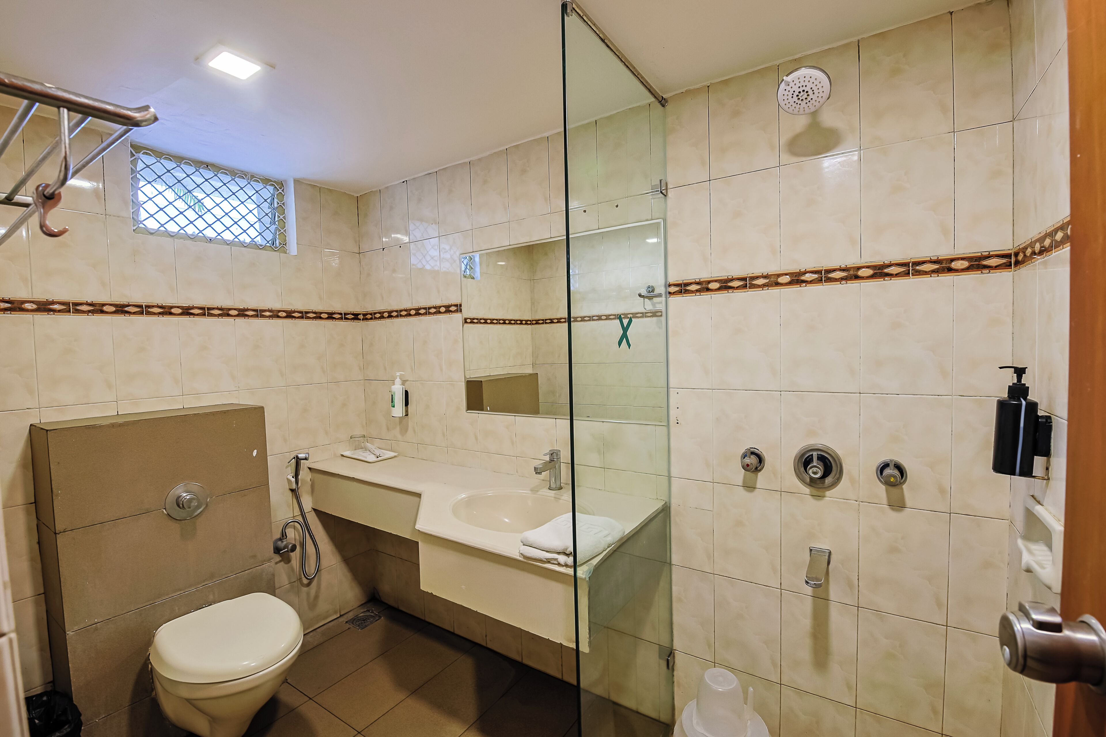 A bathroom with a toilet, sink, shower, and glass partition.