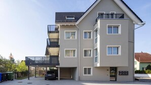 A multi-story residential building with a flat roof, balconies, and a garage.