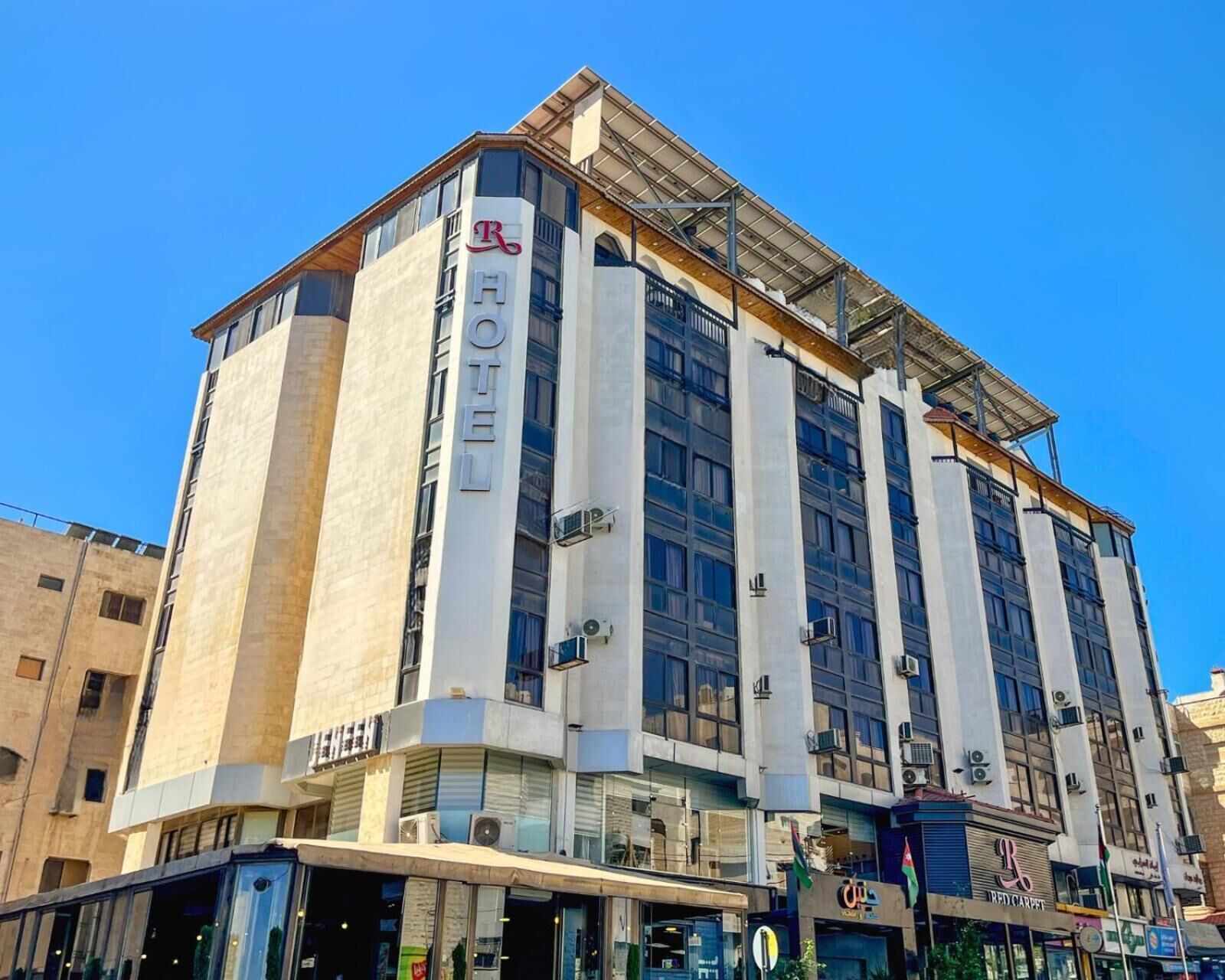 Ein Hotel mit modernem Design, das große Fenster und ein markantes 'HOTEL'-Schild an der Fassade zeigt.