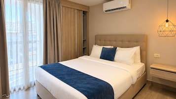 Une chambre d’hôtel avec un lit, un appareil de climatisation, un luminaire suspendu et une vue par la fenêtre.