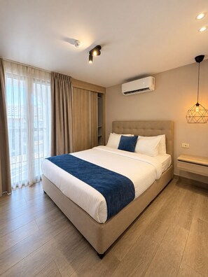 Habitación de hotel con cama, aire acondicionado, una lámpara colgante y vistas por la ventana.
