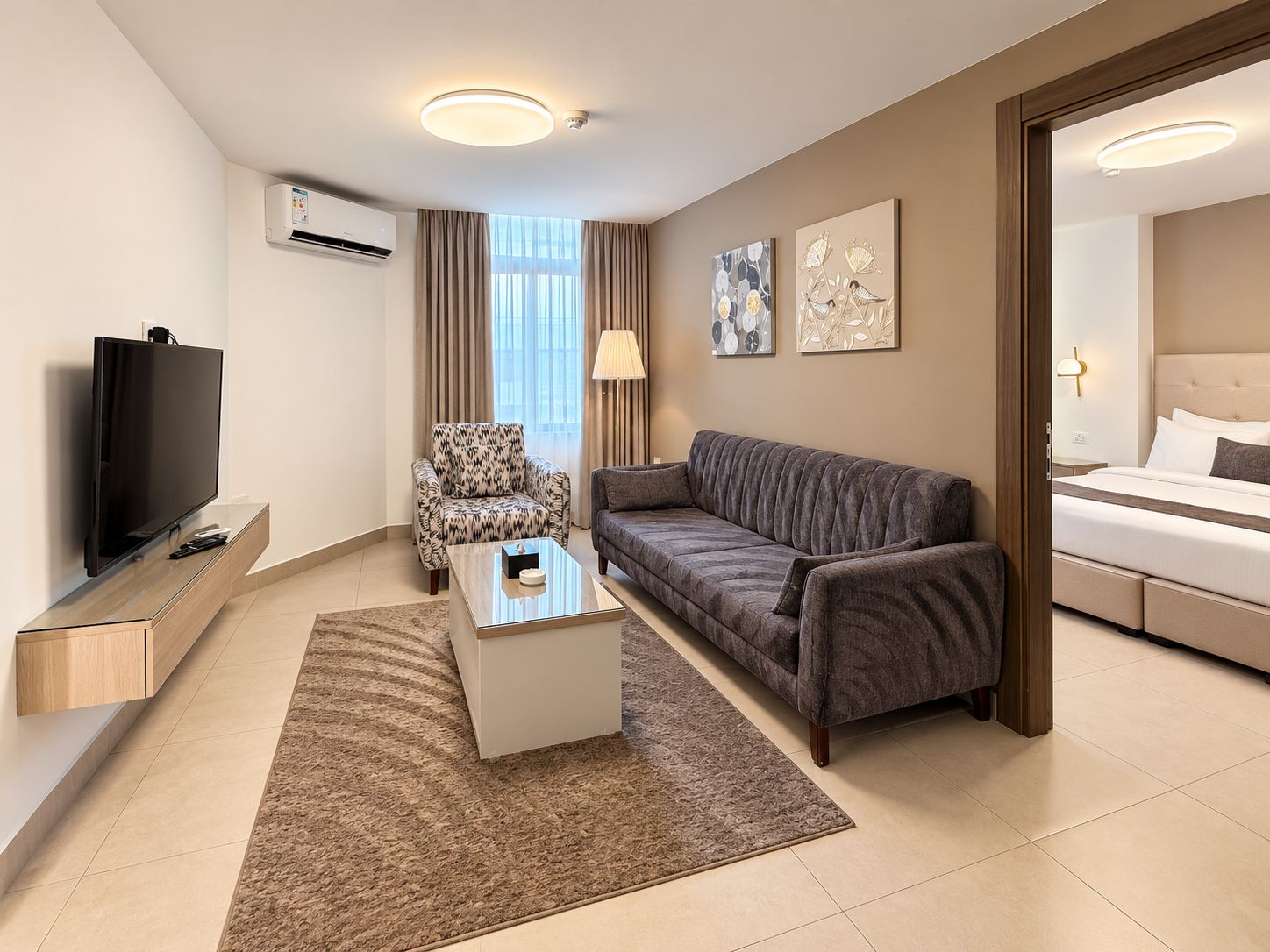 Une chambre d’hôtel moderne équipée d’une télévision à écran plat, d’un canapé, d’une table basse et d’un lit.