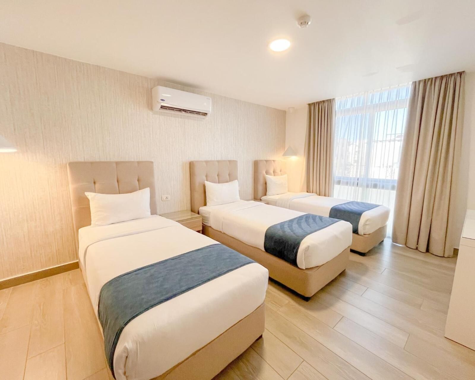 Habitación de hotel con dos camas, un televisor de pantalla plana y un ventanal con cortinas.