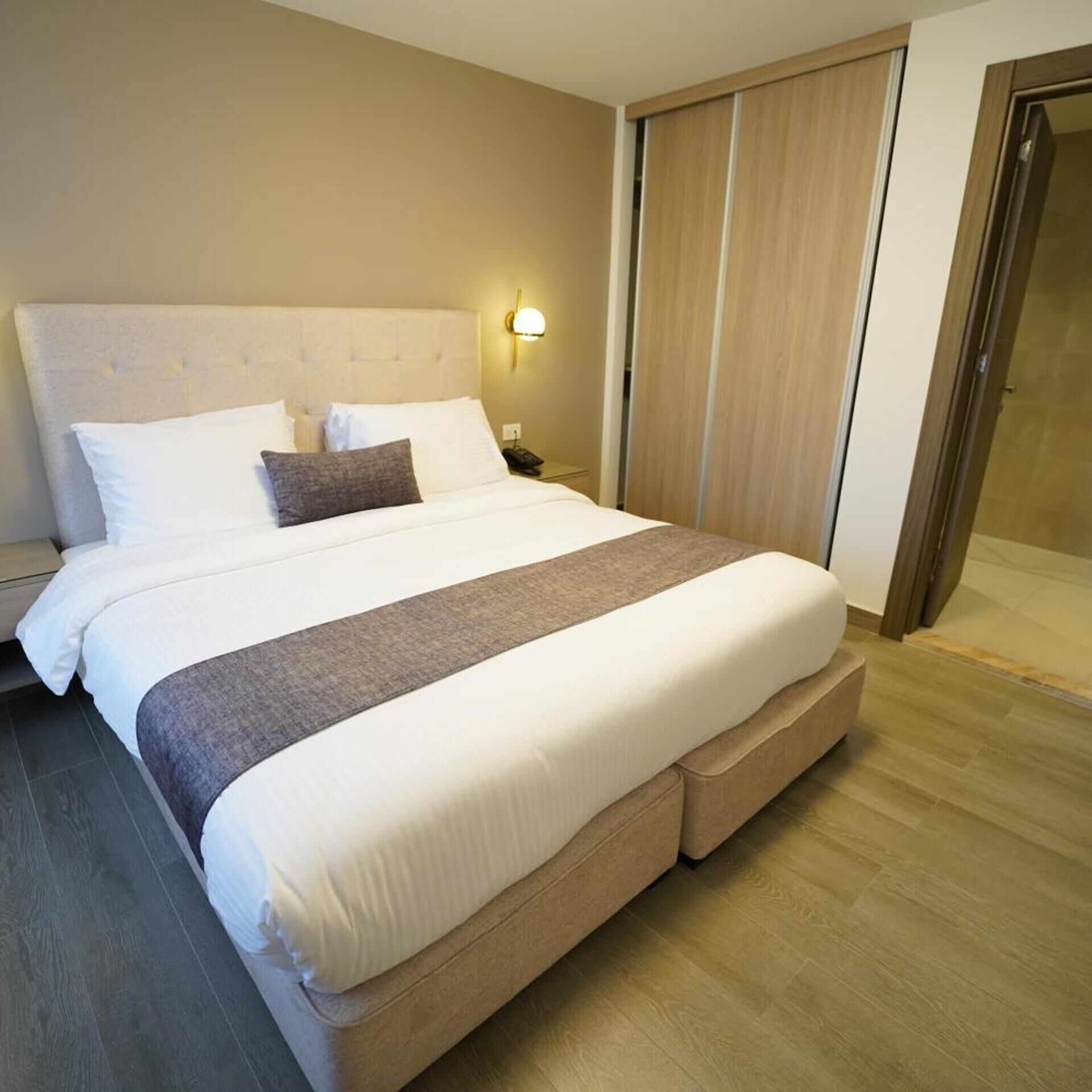 Ein Hotelzimmer mit einem großen Bett, einem Nachttisch, einer Lampe und einem Schiebetürenschrank.