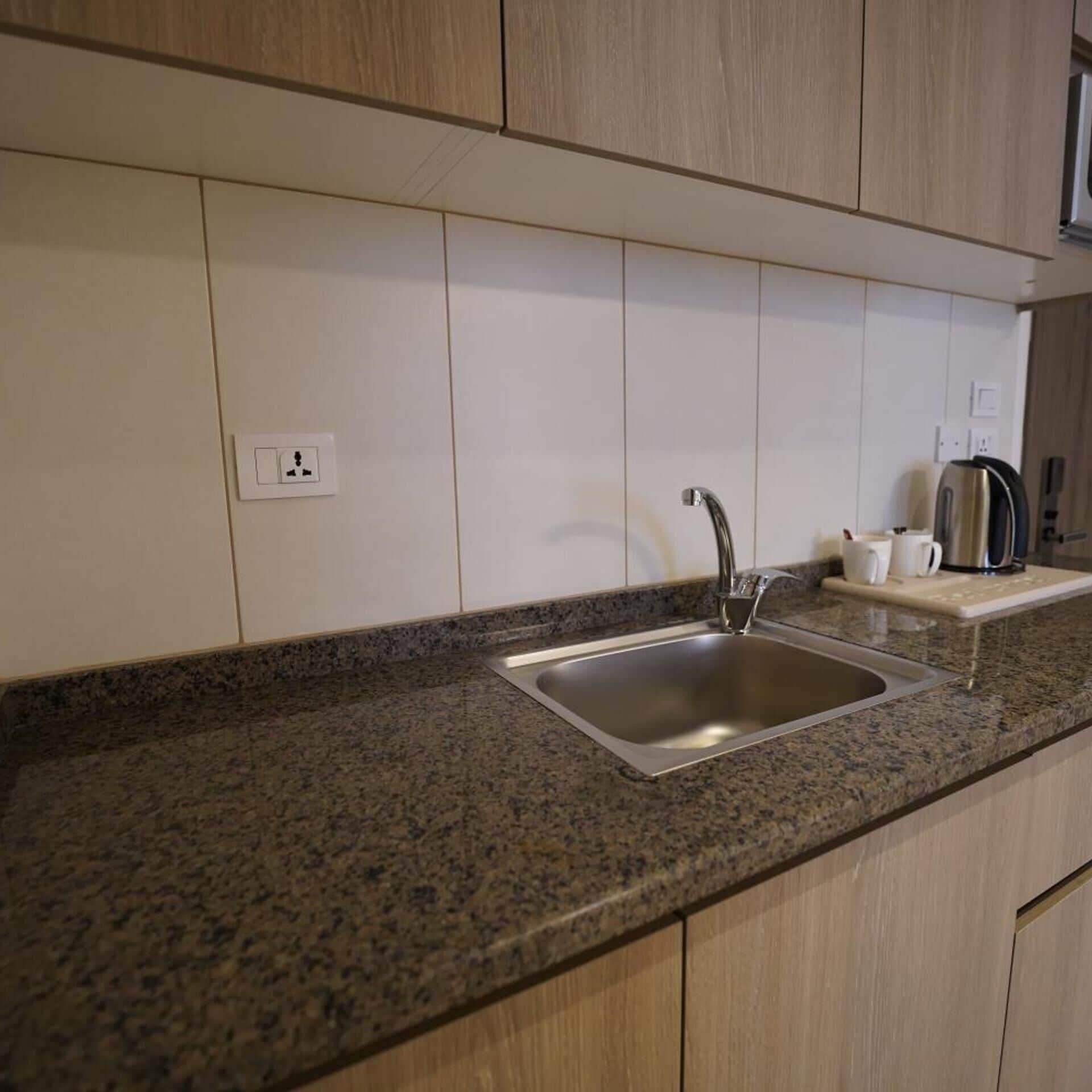 Una cocina con encimera de granito, pileta de acero inoxidable y muebles de madera.