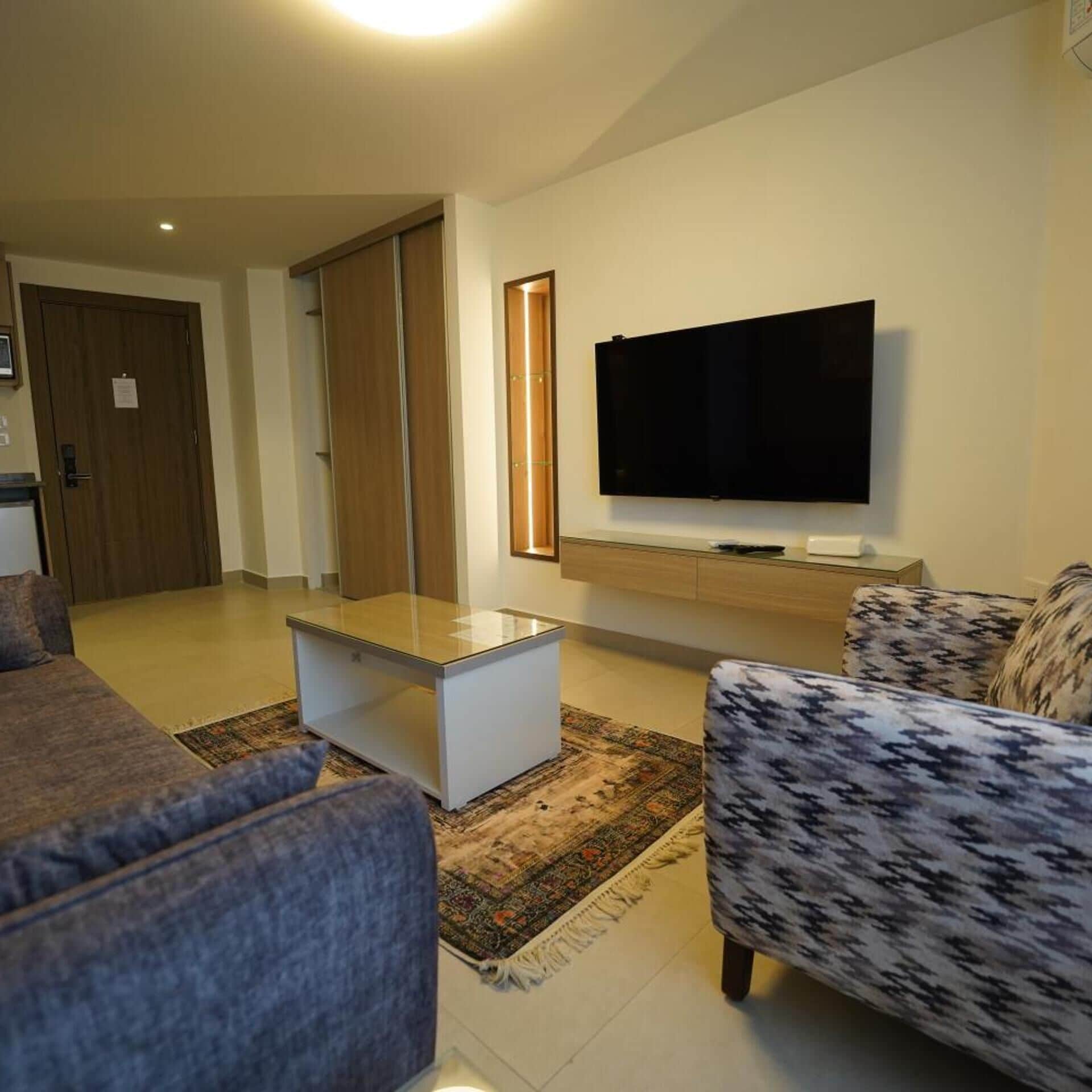 Una sala de estar moderna con un televisor de pantalla plana, una mesa de centro y sofás estampados.