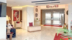 A hotel lobby with a reception desk, seating area, and a red carpet leading to the entrance. - Red Carpet Hotel & Suite (Amman)