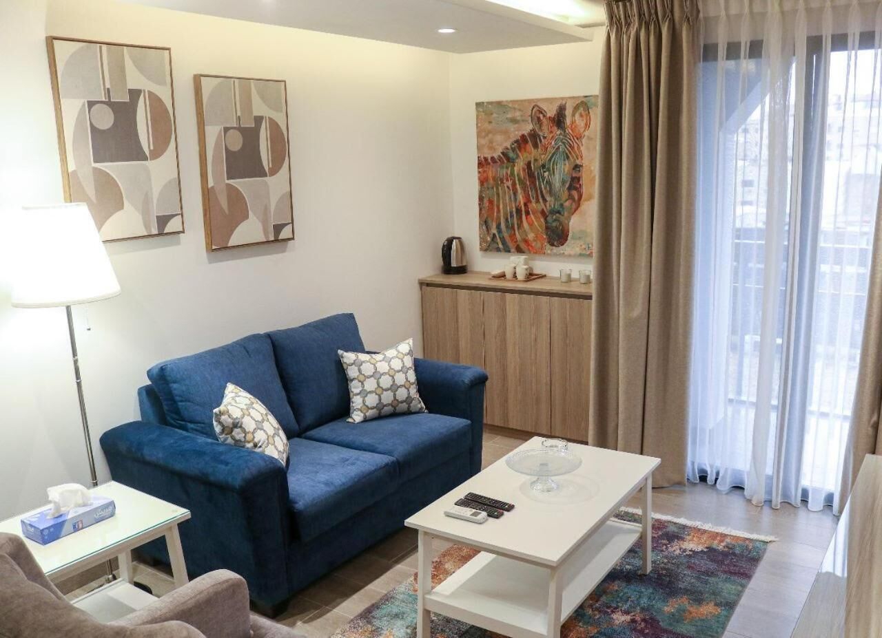 Ein Wohnzimmer mit einem blauen Sofa, einem weißen Couchtisch und einem Zebra-Gemälde an der Wand.