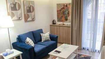 A living room with a blue sofa, a white coffee table, and a painting of a zebra on the wall.