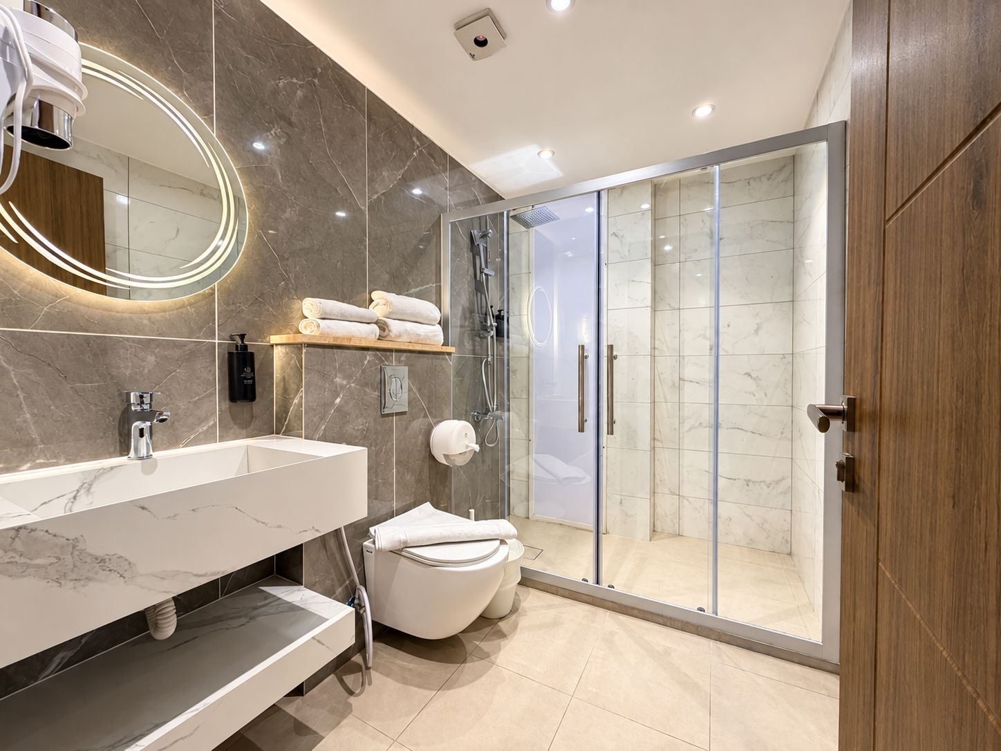 Une salle de bain moderne avec un meuble-lavabo en marbre, une douche à parois de verre et des toilettes.