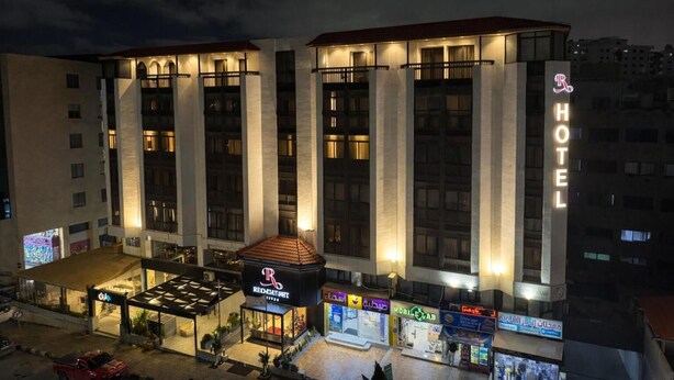 A hotel with a prominent 'HOTEL' sign, a covered outdoor area with seating, and a 'RED-KART' sign. - Red Carpet Hotel & Suite (Amman)