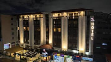 Un hotel con un llamativo letrero que dice 'HOTEL', un espacio exterior cubierto con asientos y un letrero que dice 'RED-KART'.