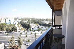 En balkon med udsigt over bybilledet, inklusive bygninger og en vej med biler.
