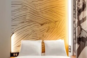 A bed with white linens and a headboard with a wavy pattern. - B&B Hotel Meaux Nanteuil-les-meaux (Nanteuil-les-Meaux)