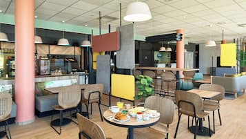 L’intérieur d’un café moderne, avec des tables et des chaises en bois, et divers types de sièges, notamment un banc et des chaises hautes.