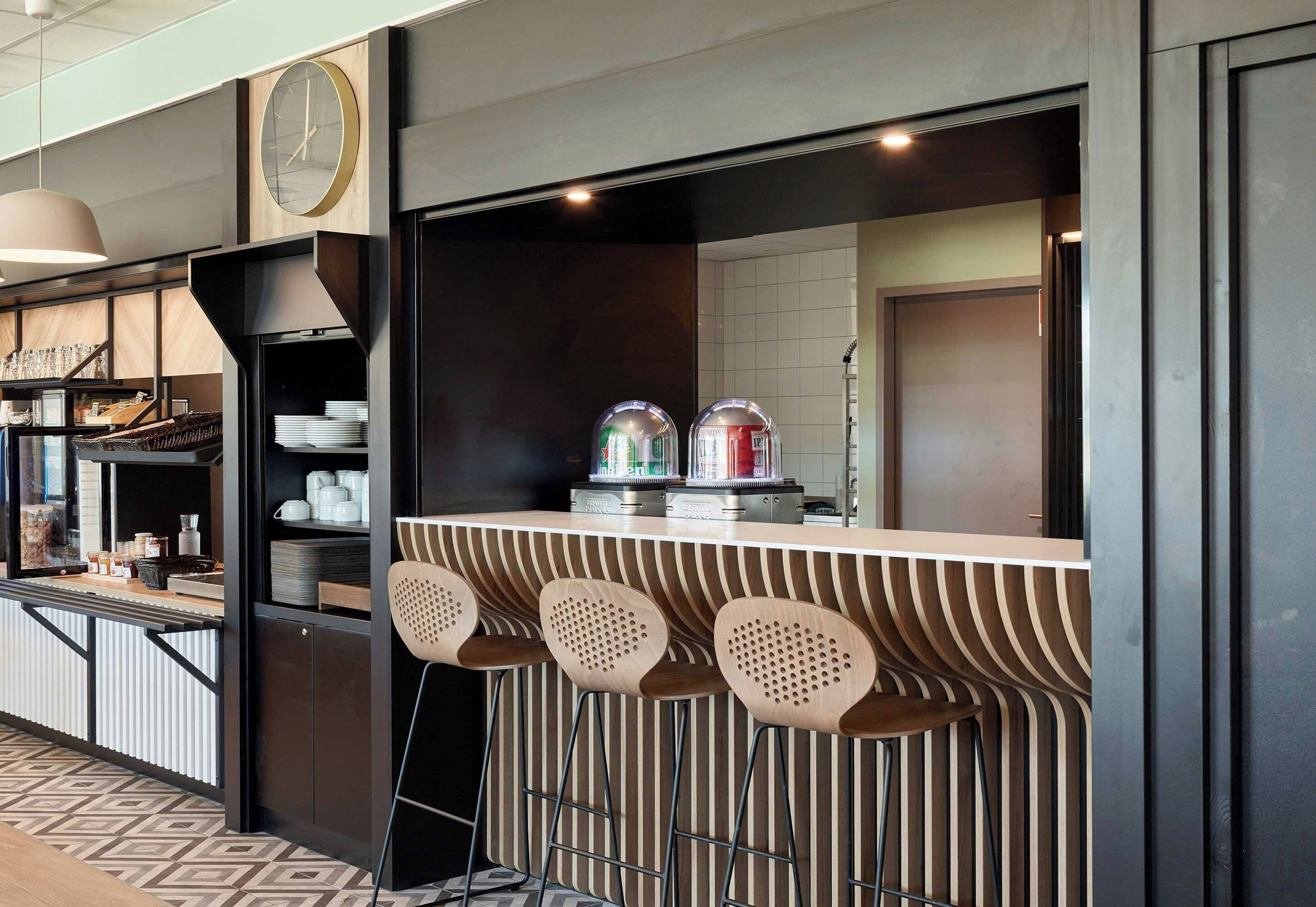 Un espace bar moderne avec un comptoir, des tabourets et une horloge.