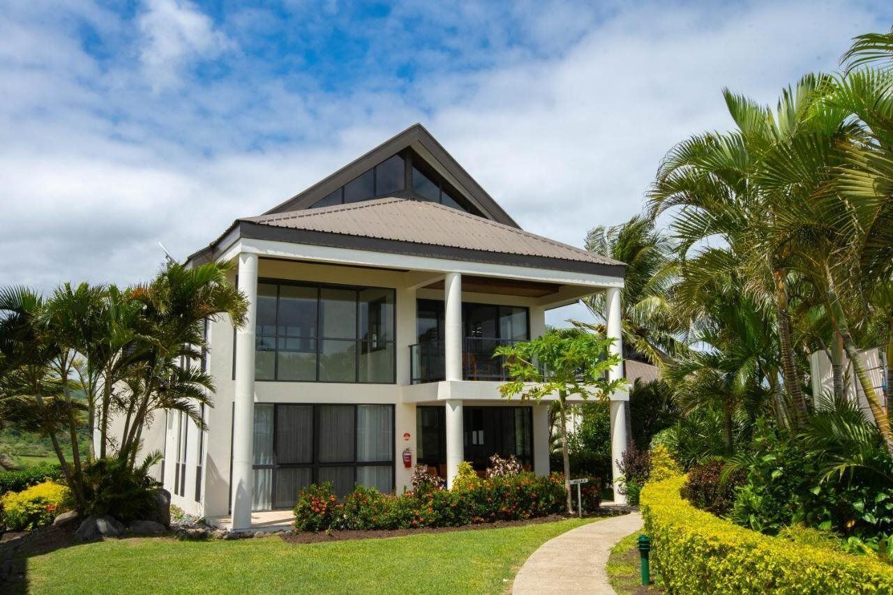 A modern two-story building with a flat roof, large windows, and a covered porch area.