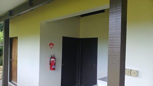 A hallway with a fire extinguisher mounted on the wall, a door, and a light switch. - Dreamview Villas (Rakiraki)