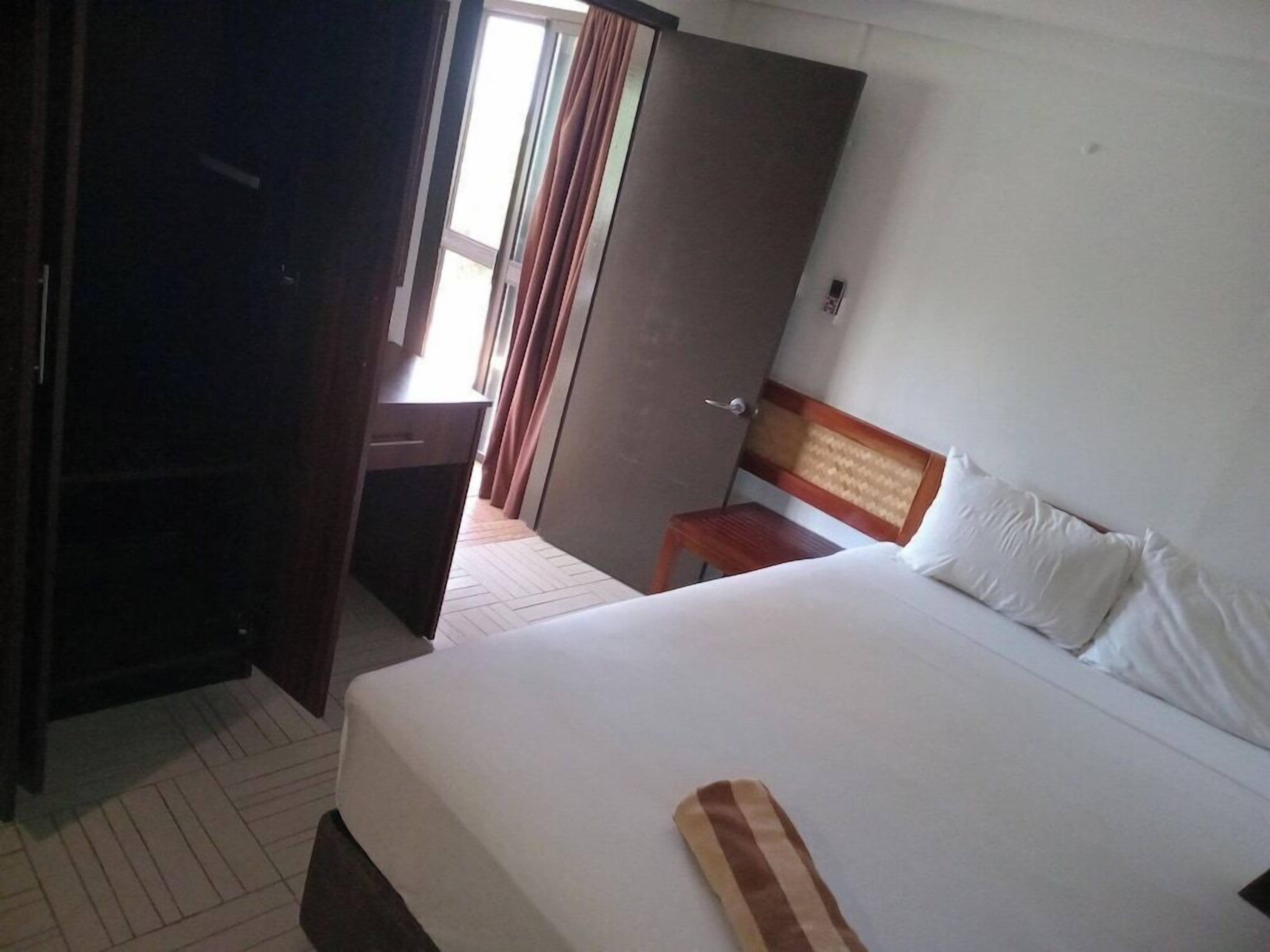 A hotel room with a bed, a desk, and a wardrobe.