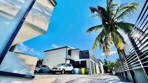 Um edifício moderno com telhado plano, fachada branca e entrada com calçada.