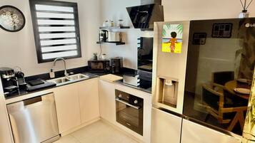 Een moderne keuken met een vaatwasser, spoelbak, magnetron en een koelkast met waterdispenser.