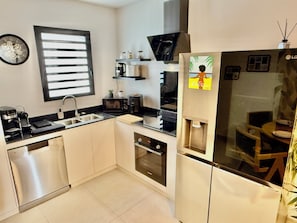 A modern kitchen with a dishwasher, sink, microwave, and a refrigerator with a water dispenser.