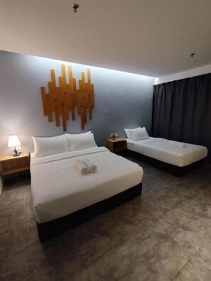 A hotel room with a large bed, a smaller bed, a nightstand with a lamp, and a wall-mounted light fixture. - Swing & Pillows @ CIQ Johor Bahru (Johor Bahru)