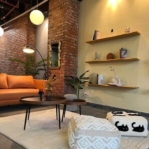 A cozy living area with a brick wall, a sofa, a coffee table, and decorative shelves. - Swing & Pillows @ CIQ Johor Bahru (Johor Bahru)
