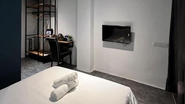 A hotel room with a bed, a desk with a chair, a television mounted on the wall, and a curtain on the window. - Swing & Pillows @ CIQ Johor Bahru (Johor Bahru)