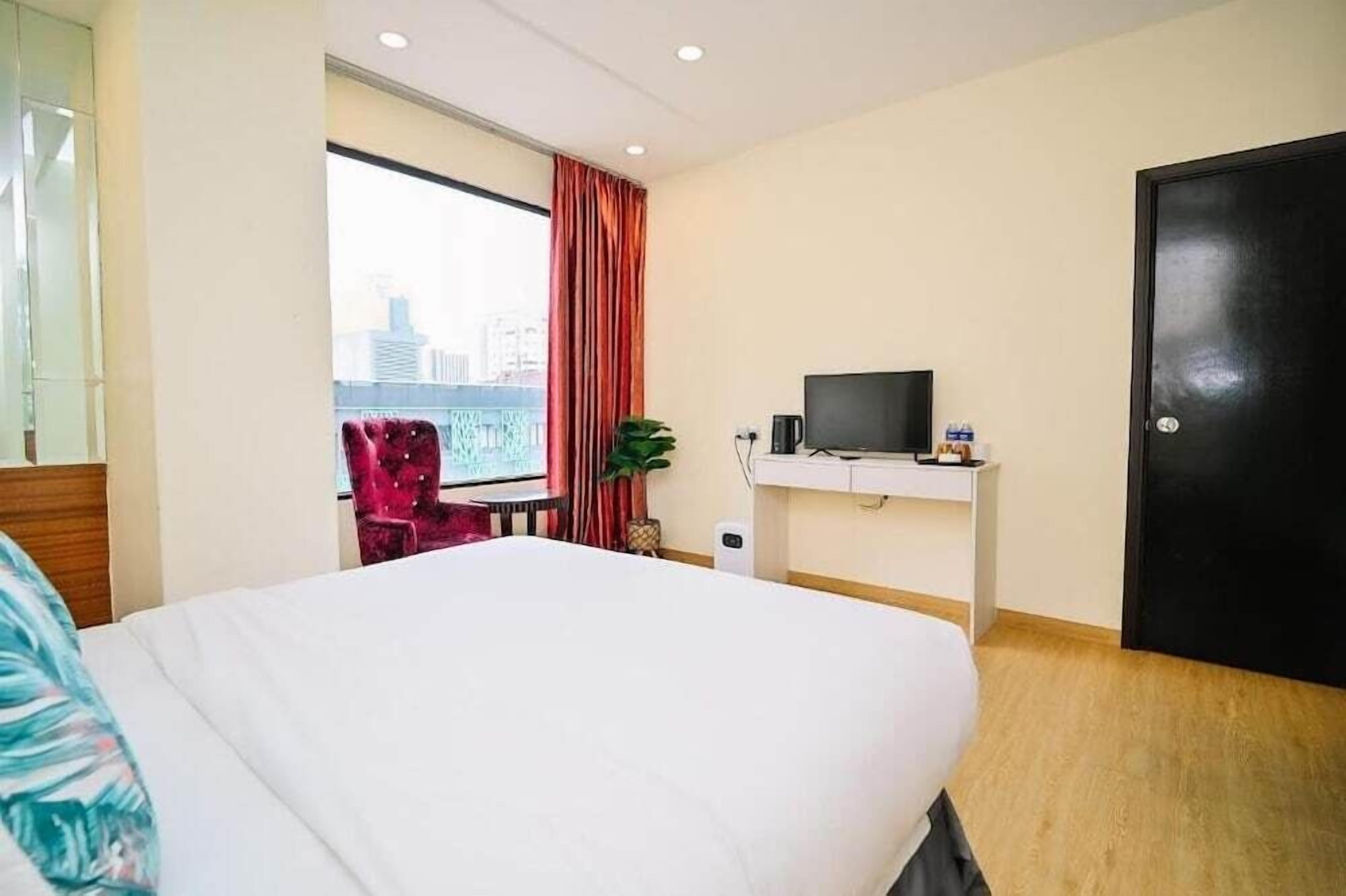 Une chambre d’hôtel avec un lit, une télévision, un bureau et une fenêtre donnant sur la ville.