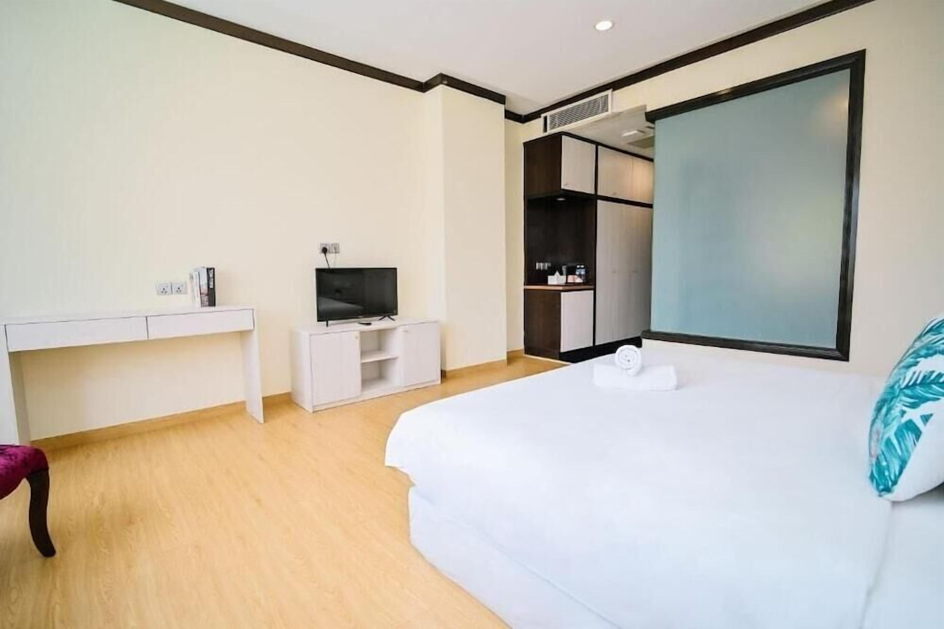 Ein Hotelzimmer mit Bett, Fernseher, Schreibtisch und Kleiderschrank.