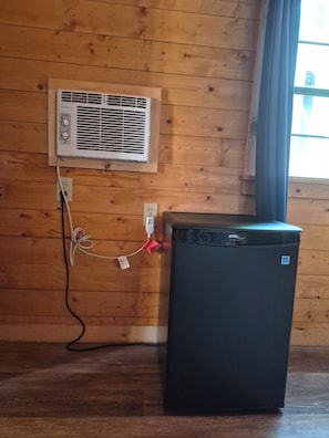 A compact refrigerator with a control panel, connected to a wall-mounted air conditioner with a power outlet. - 2 bedroom Family room with ensuite bathroom (Essex)