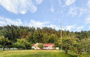 Uma casa com telhado vermelho, cercada por um gramado e uma floresta.