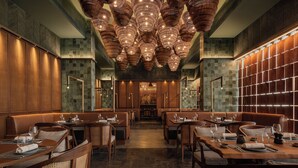 A restaurant interior with multiple dining tables and booths, a patterned ceiling, and a wall with a grid of lights. - Giza Palace (Sheikh Zayed City)