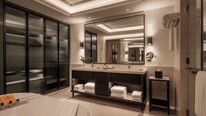 A modern bathroom with a large mirror, a vanity with a sink, and a walk-in closet with glass doors. - Giza Palace (Sheikh Zayed City)