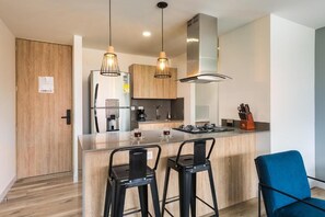A modern kitchen with a central island, bar stools, and pendant lighting. - ENZO Privé | Go Living & Suites Loft - Luxury Stay in the Heart of El Poblado (Medellín)