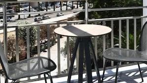 A balcony with two chairs and a table, overlooking a road and a hill with a fort-like structure. - Liberty (Nafplio)