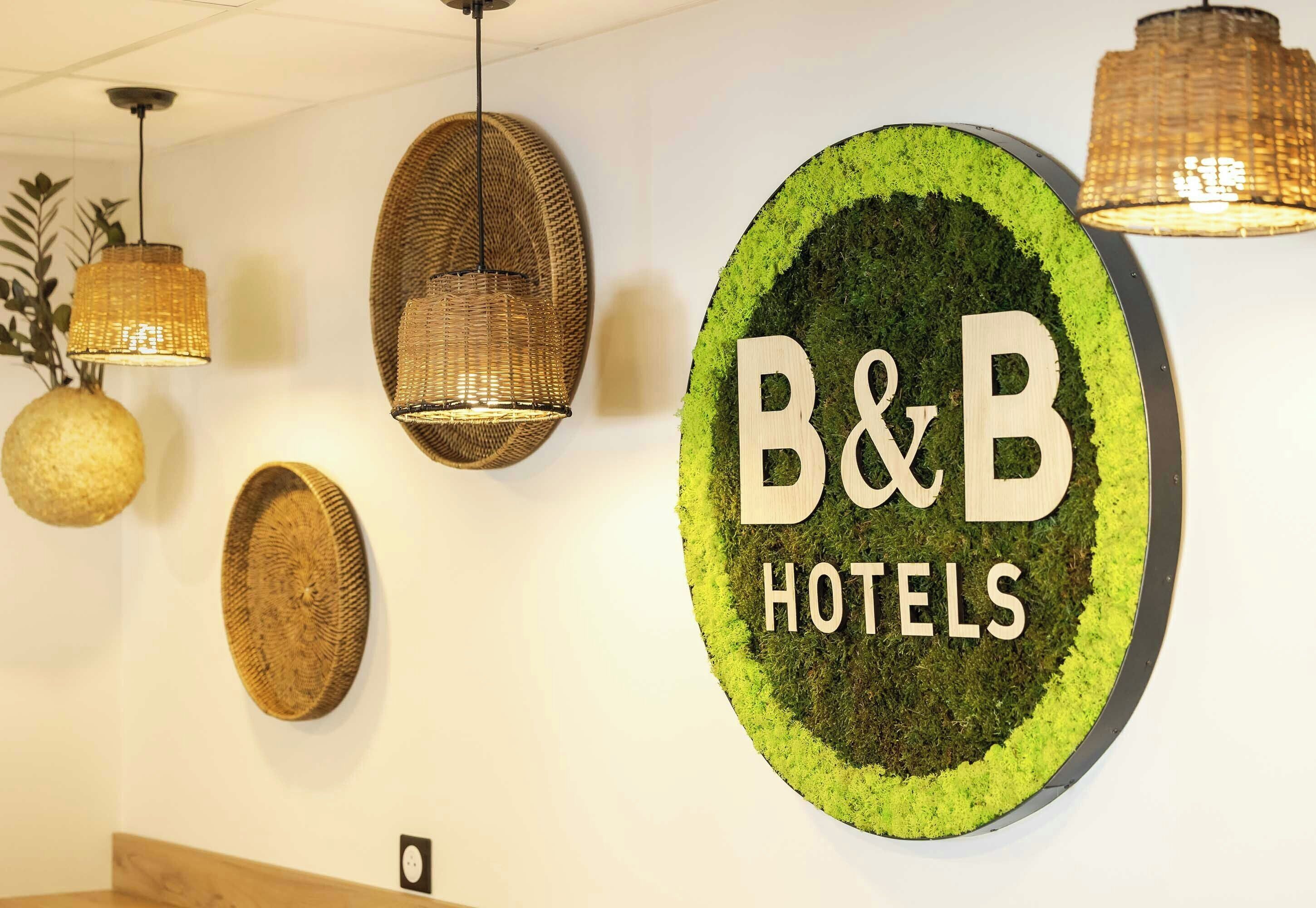 A wall with a circular sign reading 'B&B HOTELS' surrounded by woven wall art.