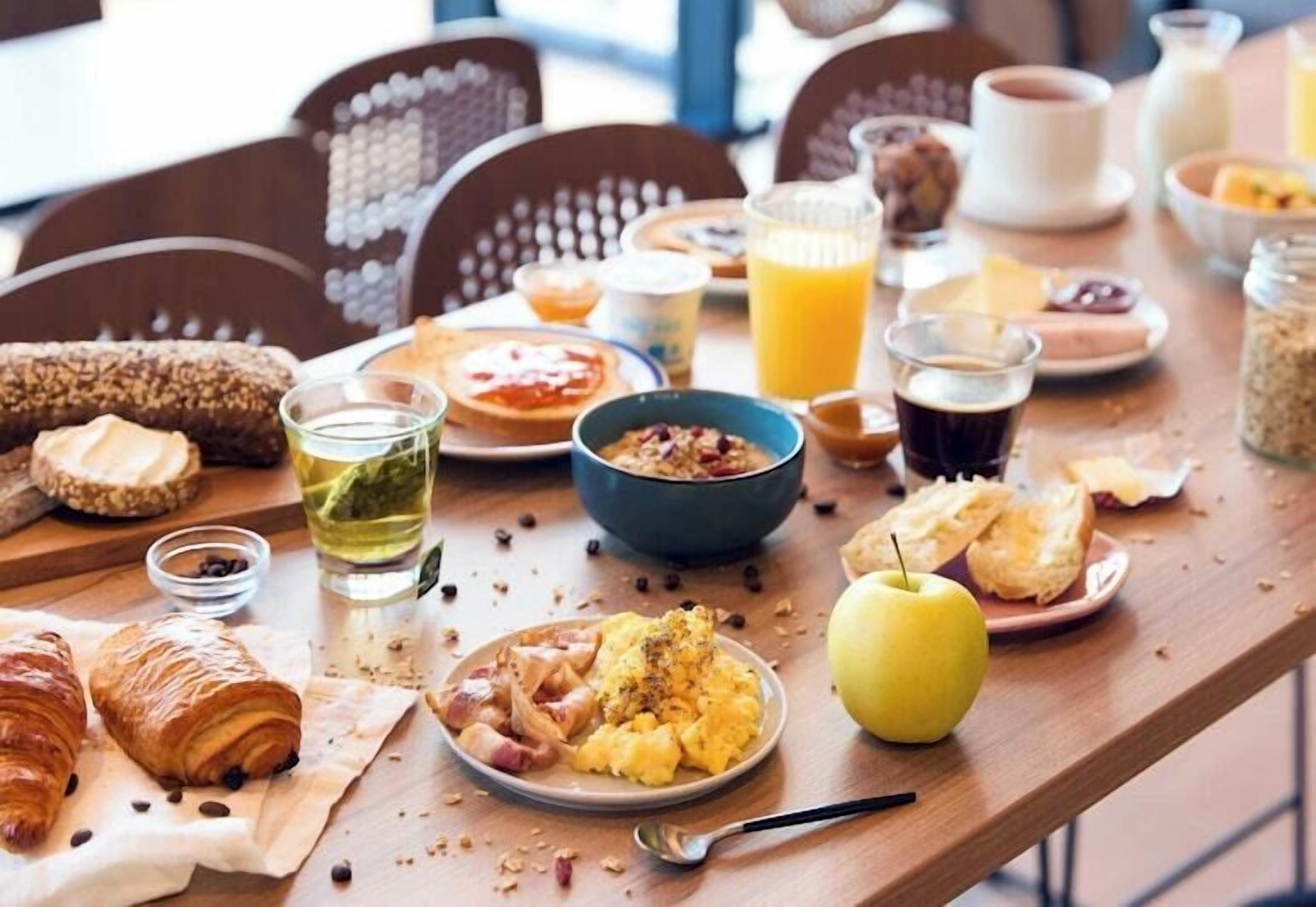 A breakfast table with various food items, including bread, eggs, and fruit.