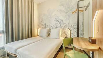 Een hotelkamer met een bed, een stoel, een bureau en een muur met een tropische muurschildering.