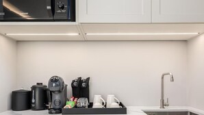 Ett modernt kök med mikrovågsugn, kaffebryggare och diskmaskin.