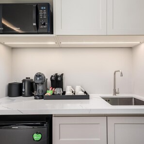 A modern kitchen with a microwave, coffee maker, and dishwasher. - Chateau Du Village Patong (Krabi)