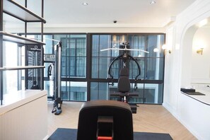 A modern gym with exercise equipment, large windows, and a reception area. - Chateau Du Village Patong (Krabi)