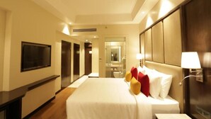 A hotel room with a large bed, a television, a mirror, and a bedside lamp. - The Vaishno Devi Sarovar Portico Katra (Reasi)