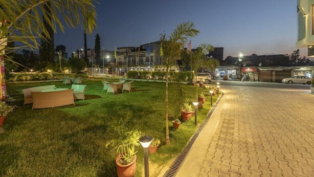 A well-lit outdoor area with a paved walkway, seating arrangements, and potted plants. - The Vaishno Devi Sarovar Portico Katra (Reasi)