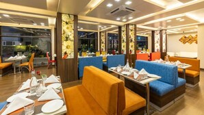 A restaurant interior with booths and tables, some with menus and glasses. - The Vaishno Devi Sarovar Portico Katra (Reasi)