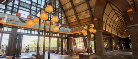 An indoor space with a high arched ceiling, large windows, and hanging spherical light fixtures.