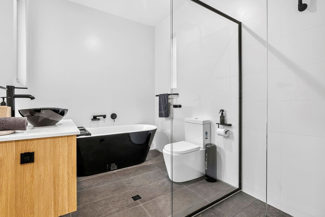 Un baño moderno con una bañera independiente, un inodoro y un lavabo con un recipiente grande.