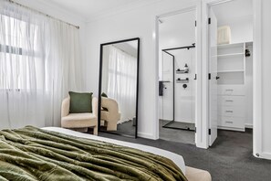 Un dormitorio con una cama, una silla, un espejo y un armario.