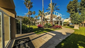 A hotel entrance with a well-maintained lawn, palm trees, and a clear sky. - Hotel Nautilus Excelsior - Adults Only (Cagliari)